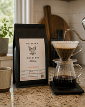 Load image into Gallery viewer, A black bag of No Sleep Roastery Costa Rica coffee sits on a granite kitchen counter next to a glass pour-over coffee maker with water being poured from a metal kettle.