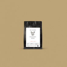 Load image into Gallery viewer, Fresh roasted coffee in a black bag with a white label displayed on a beige background