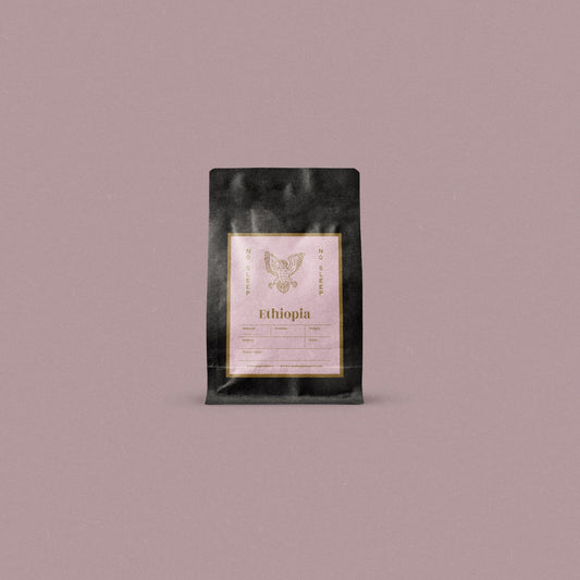 A single black coffee bag with a central cream label reading 'Ethiopia' and a owl logo, centered on a solid dusty mauve background.