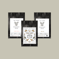 Fresh roasted coffee in a three black bags with a white labels displayed on a light beige background